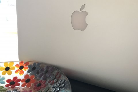 MacBook von hinten, mit einer Blumenglasschale davor